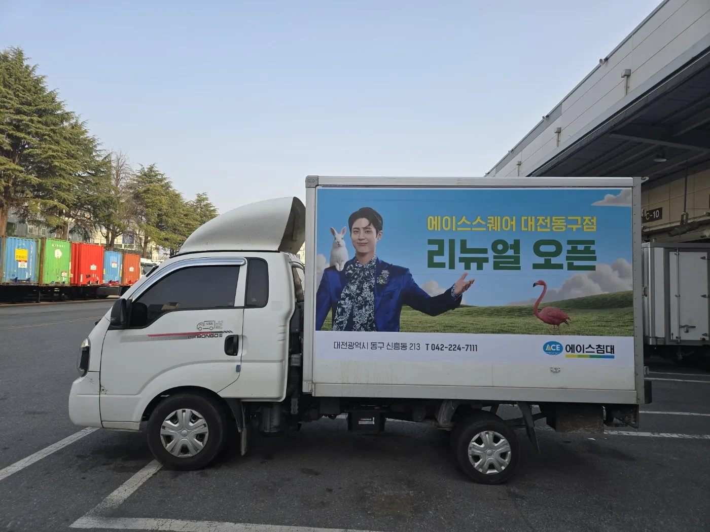 하늘색 배경의 에이스스퀘어 대전동구점 리뉴얼 오픈 광고 탑차 측면